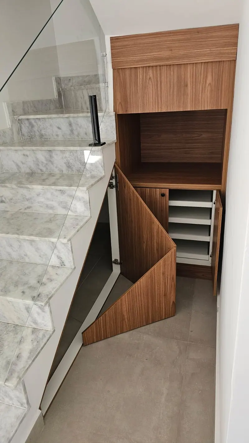 Armário sob a escada com portas e nichos aproveitando o espaço
