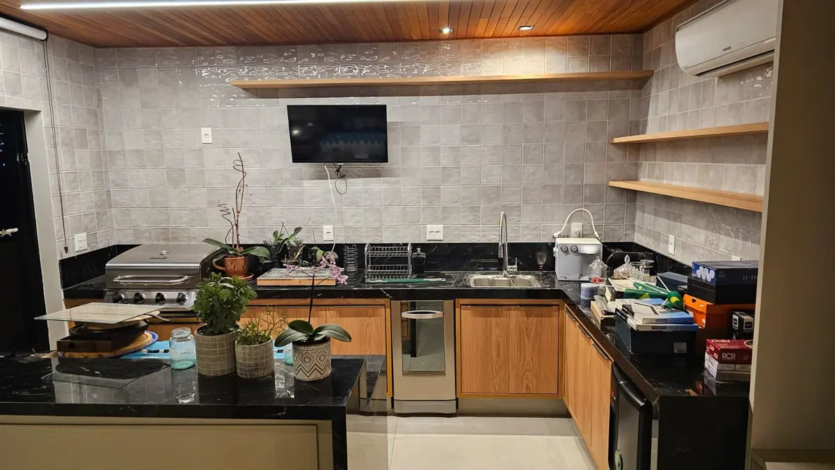 Espaço gourmet em U com armários amadeirados e granito preto